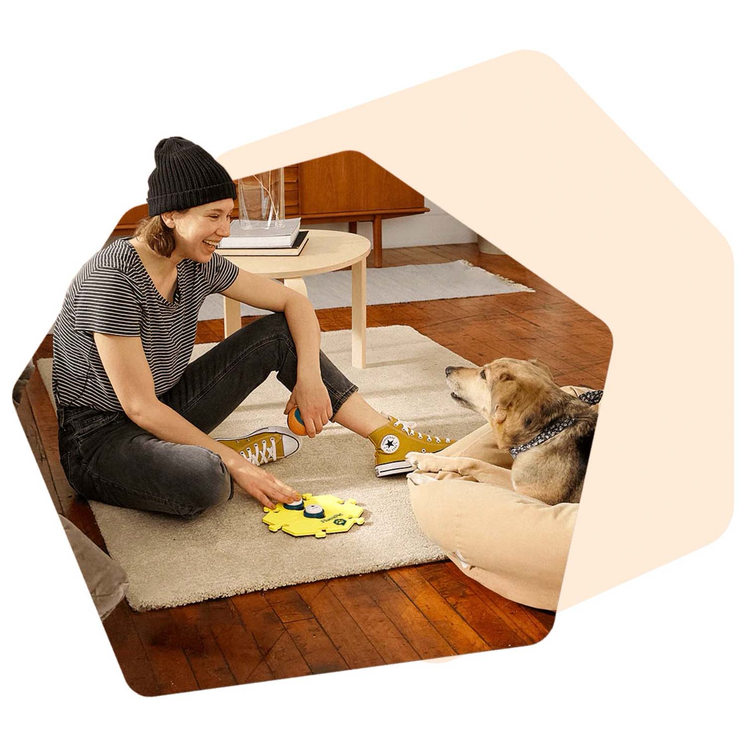 A young woman teaching her dog to talk using a FluentPet button in a HexTile.