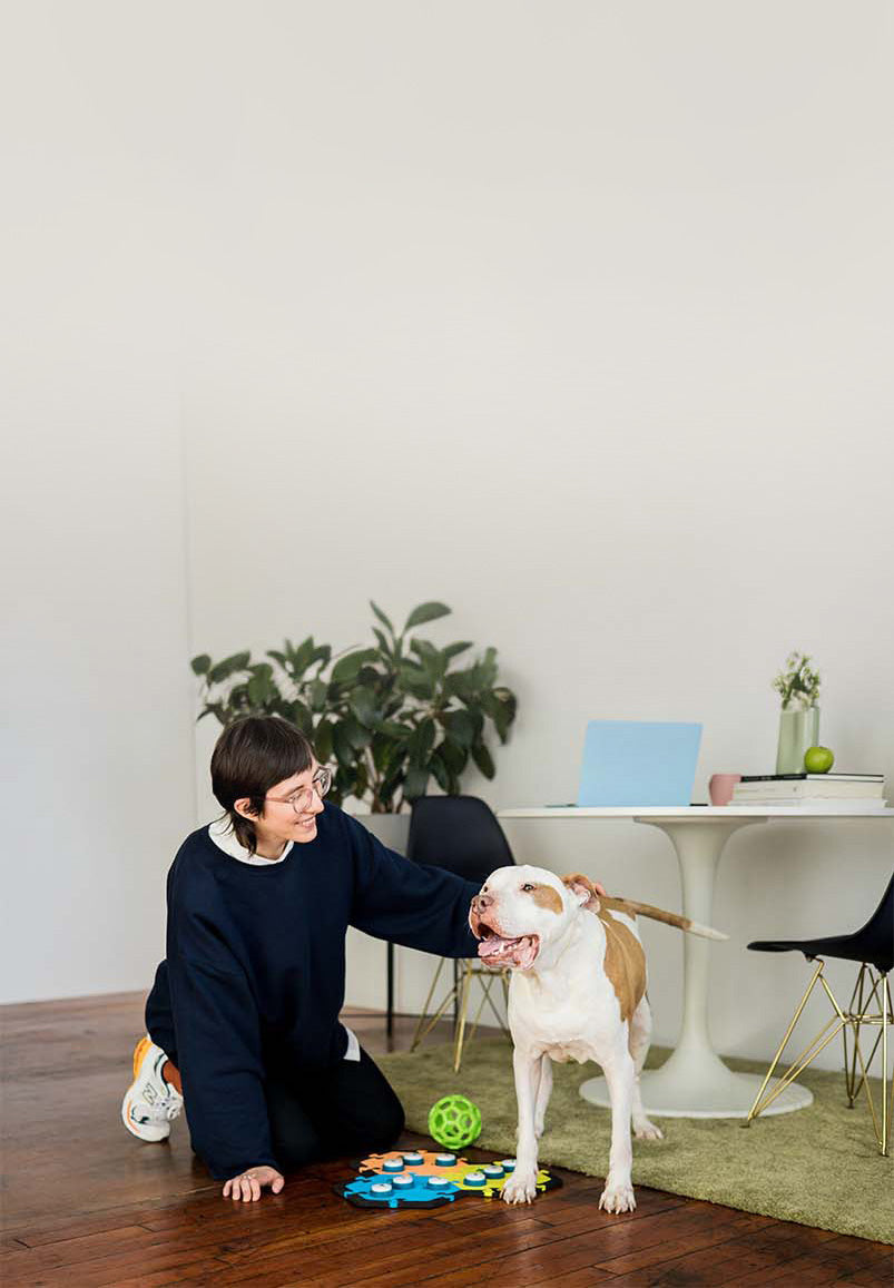 A young woman petting her dog, who is using the FluentPet Talking Button System.